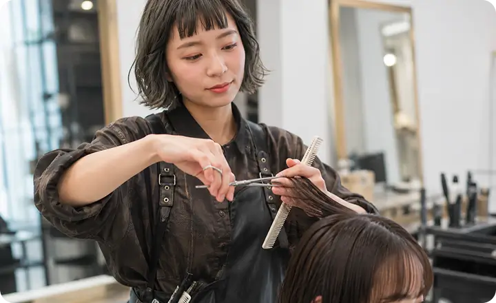 女性美容師がヘアカットをしている様子